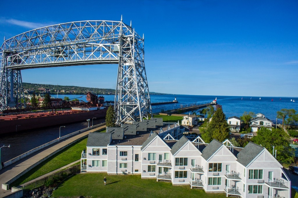 A ship passing through the Aerial Lift Bridge in Duluth, MN with sailboats watching in the distance