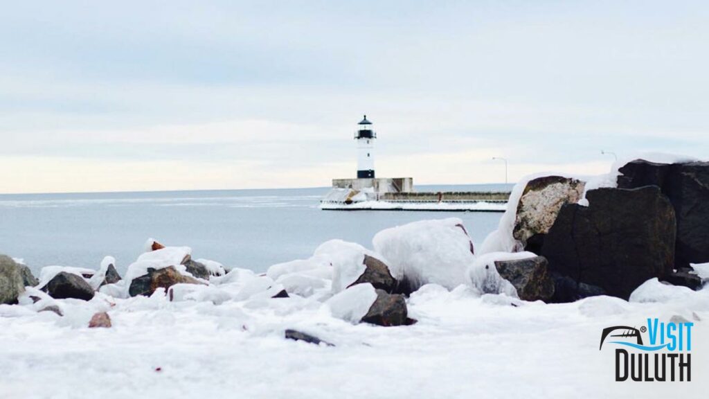 A winter scene of the lighthouse and ice-covered rocks in Canal Park.