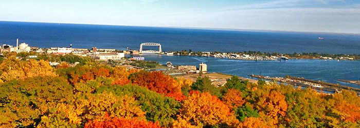 Trees in full autumn colors with blue Lake Superior and the Aerial Lift Bridge in the distance.