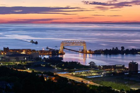 An early morning sunrise with a ship coming into duluth's aerial lift bridge. The bridge's road is raised.