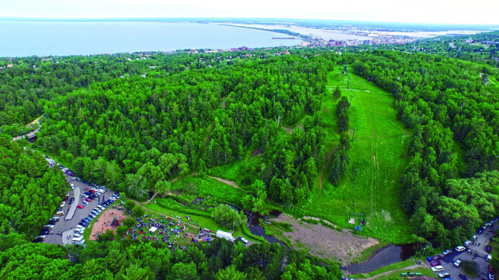 Aerial view of chester bowl ski hill in summer. The grass and trees are vibrant green and crowd is in the playground.