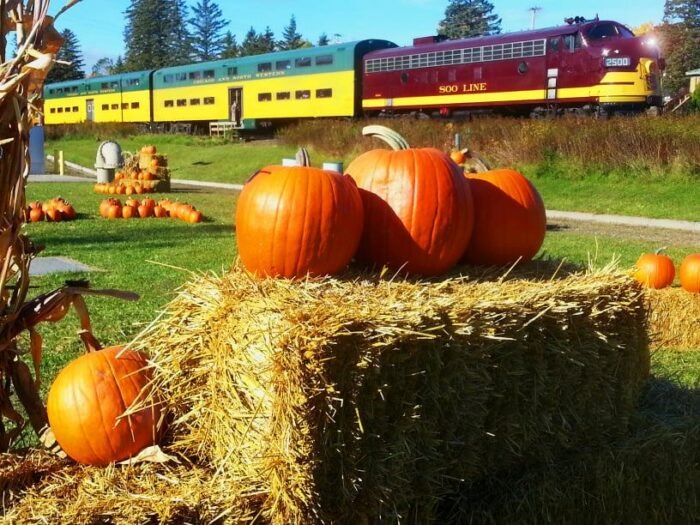 Outside the Great Pumpkin Train with hay bails and pumpkins.