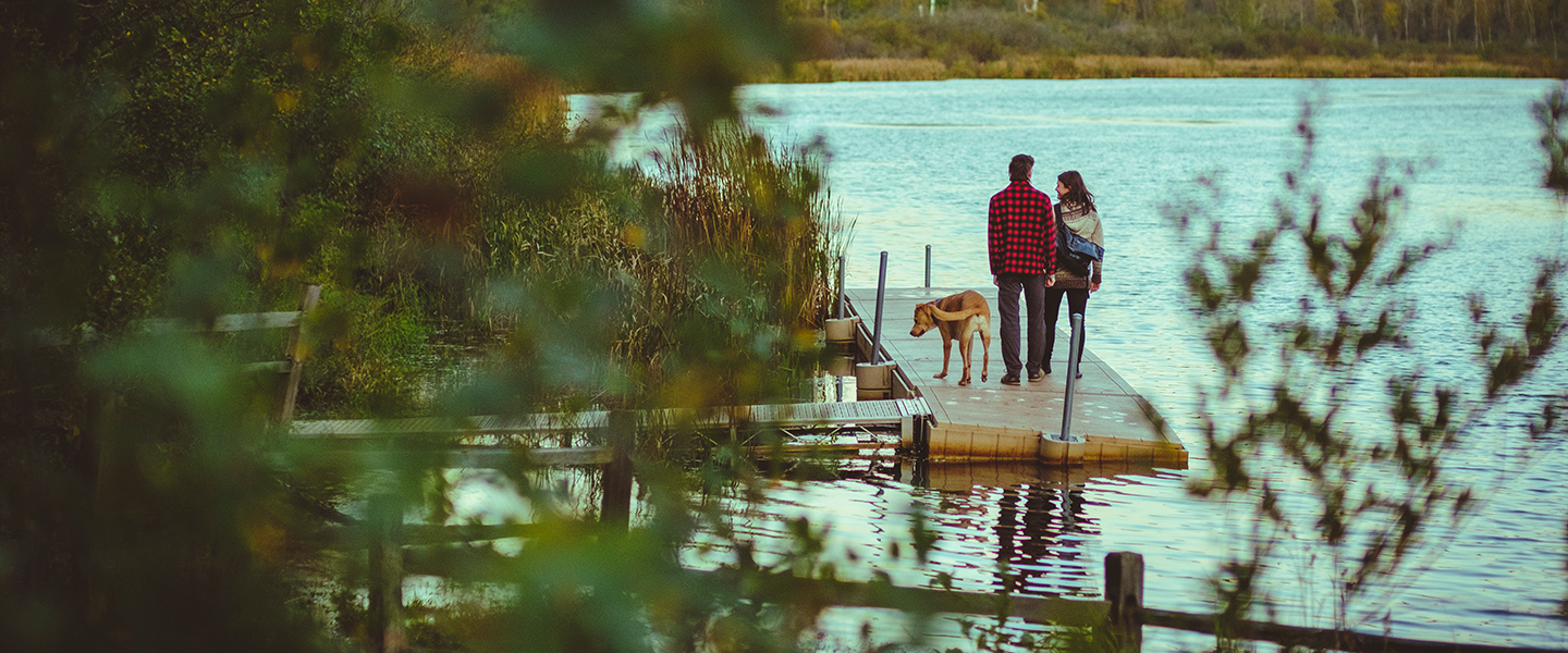 people and a dog standing on a dock