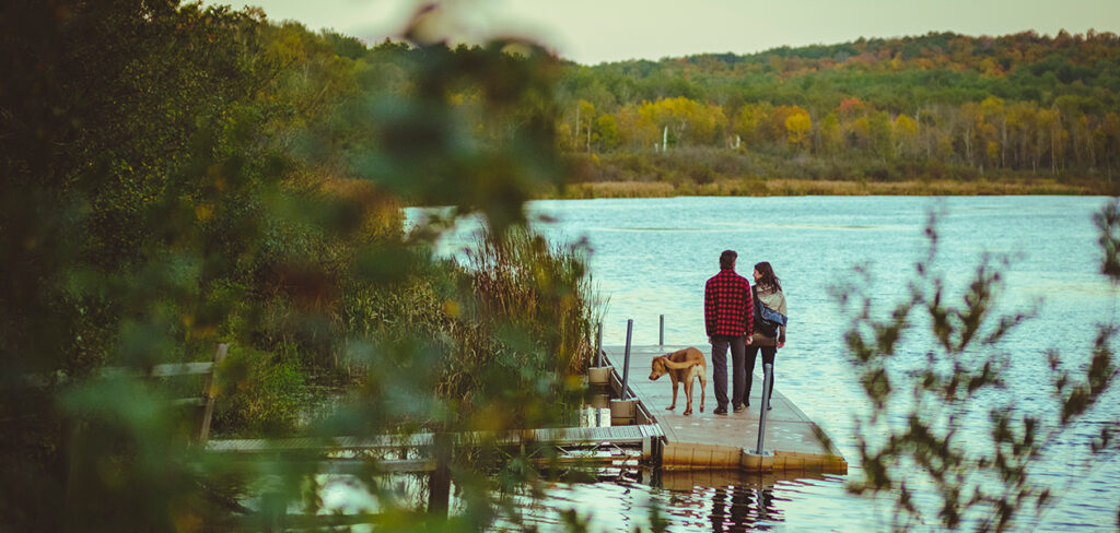 A couple walking on the dock with their dog