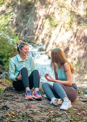 Friends talking on a rock by a waterfall