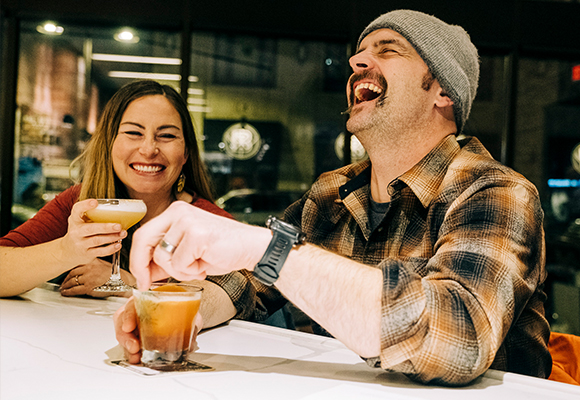 two people laughing having a drink