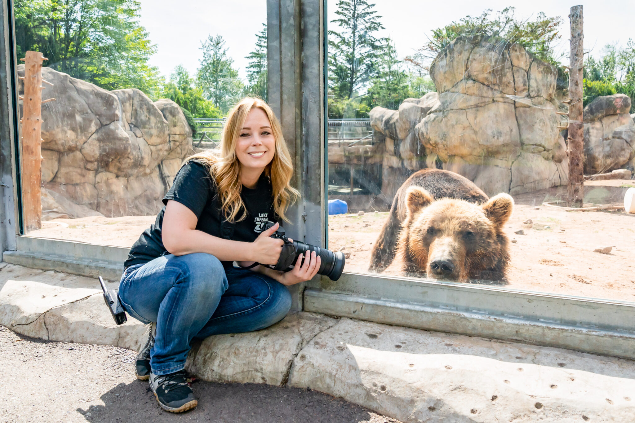 Heidi Beal poses with her camera in front of a bear