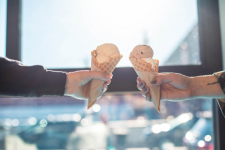 two people cheersing ice cream cones