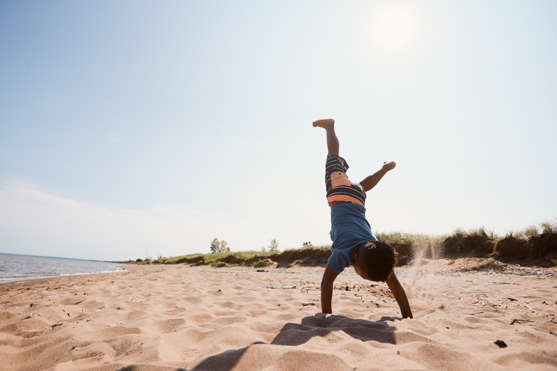 A kid does a cartwheel in the sand