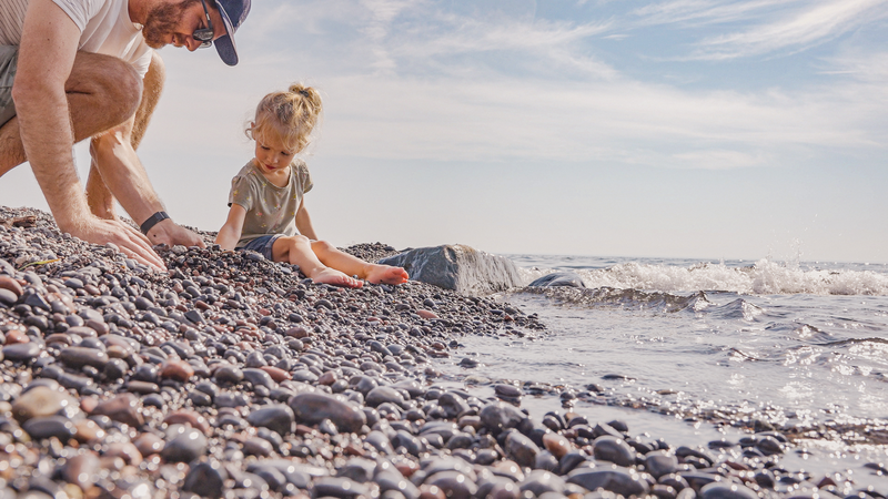 A kid plays in rocks on the lakeshore