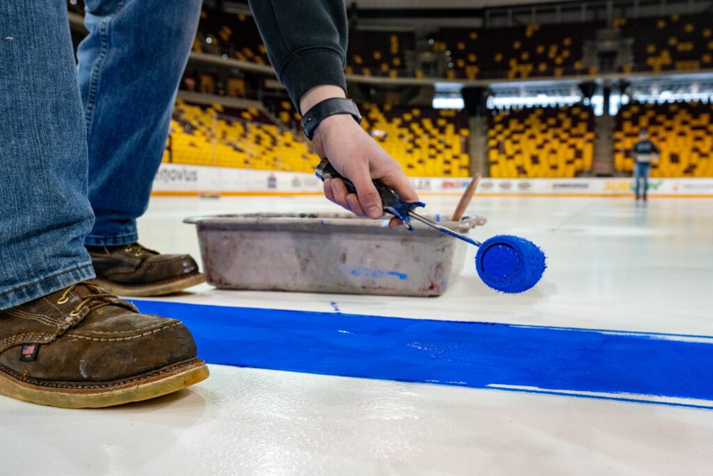 Jake paints the blue lines on the ice