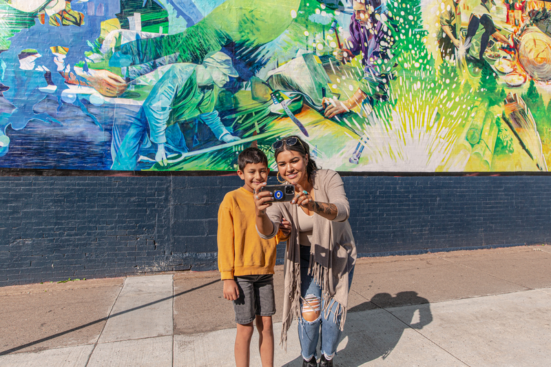 A mother and son taking a photo in front of a mural