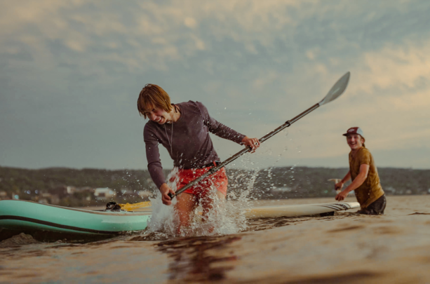 Couple splashing water while paddle boarding