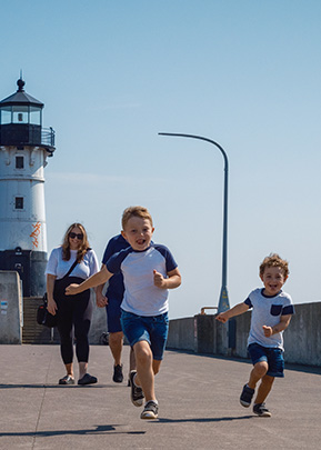 kids running with a lighthouse in the background