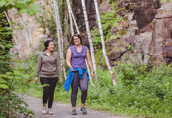 two friends walking on a wooded trail