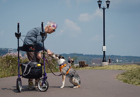 elderly woman walking her dog on a paved path