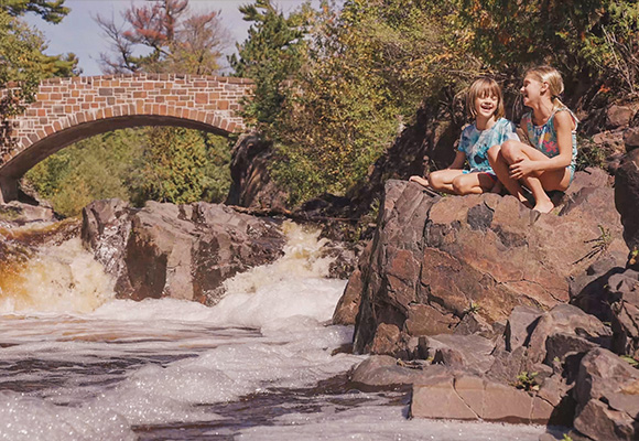 Two girls laughing by a waterfall