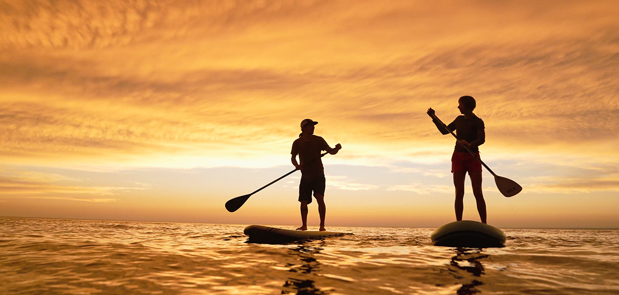 Two people paddle boarding during the sunset