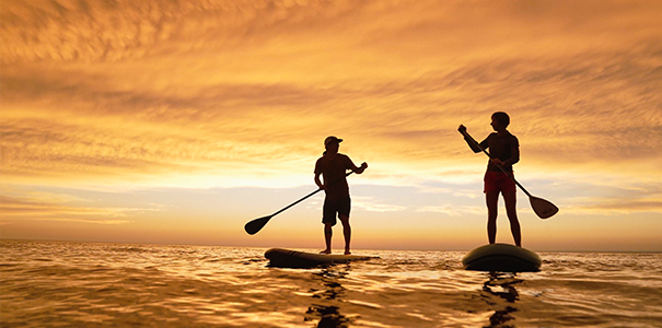 Two people paddle boarding during the sunset