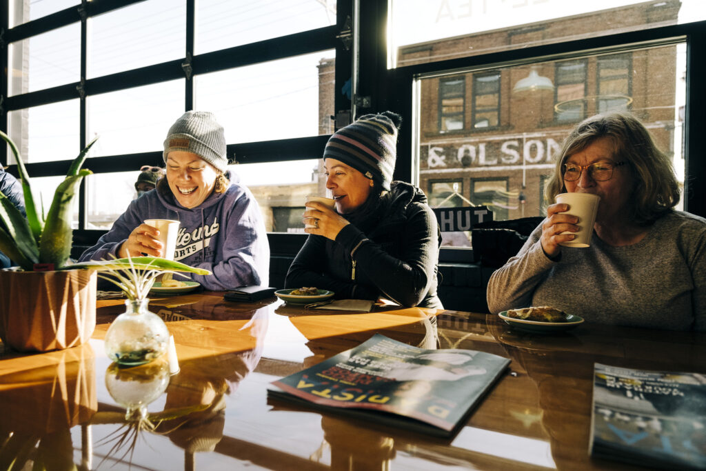 three people sitting in a cozy coffee shop drinking warm beverages