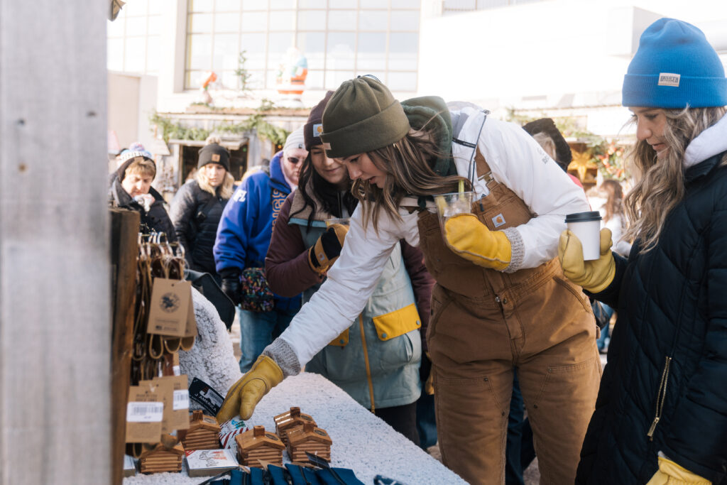 woman in warm coveralls, hat and mittens shopping at an outdoor market