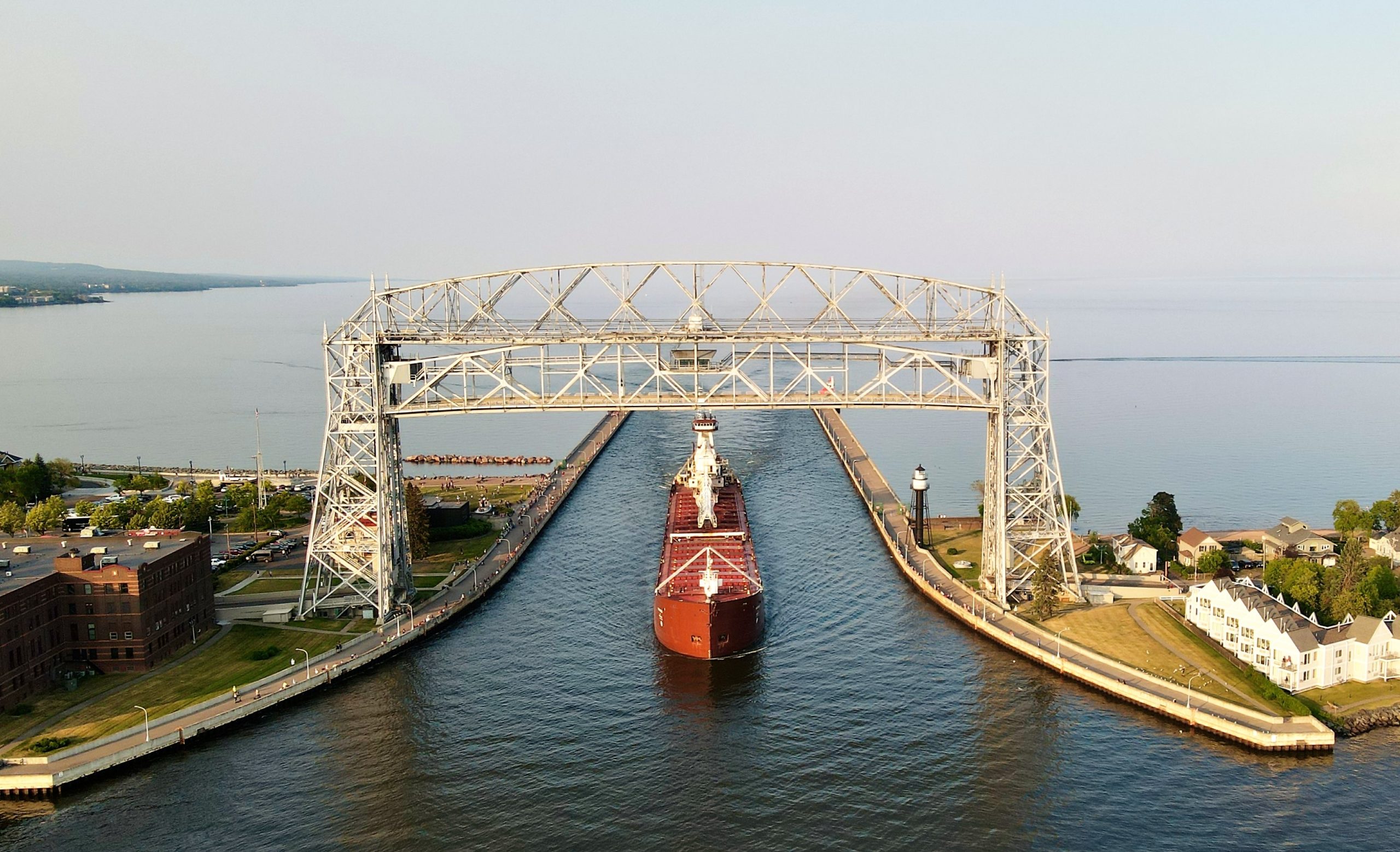 Aerial drone view of a freighter ship passing through the Duluth Ship Canal beneath the raised Aerial Lift Bridge