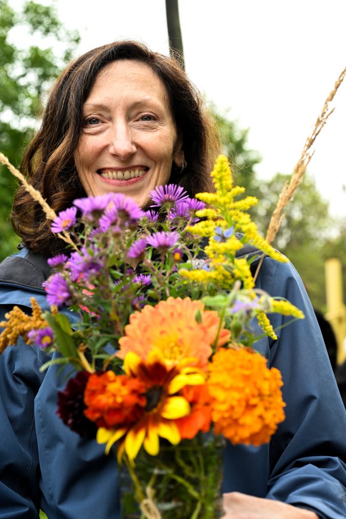 Chester bowl fall fest returns to duluth 5 Festival-goer smiling while holding a colorful jar of fresh autumn flowers at chester bowl fall fest in duluth, mn.