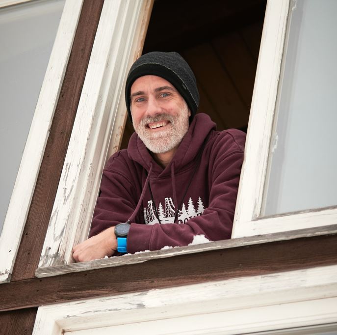 Chester bowl fall fest returns to duluth 8 Dave schaeffer, executive director of chester bowl improvement club, wearing a beanie and maroon hoodie while smiling out a wooden window.