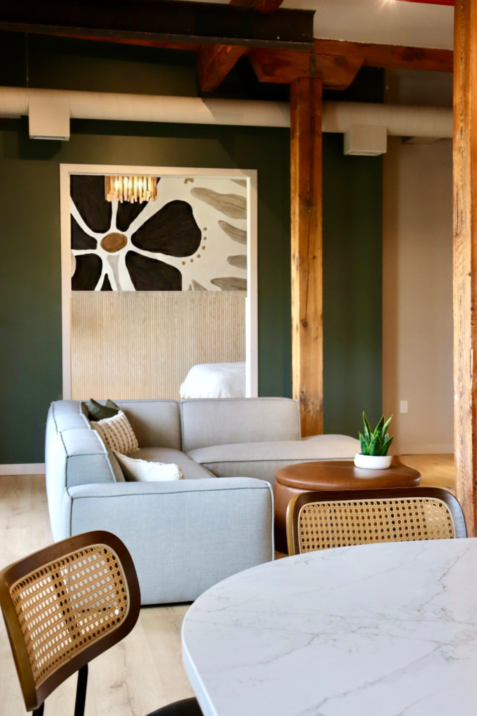 The brix: a different kind of stay in duluth 9 Living room space inside the brix aerial lofts featuring a grey sectional, leather ottoman, dining seating, and original exposed timber beams.