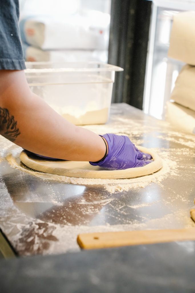How vitta pizza became a duluth favorite 2 Hands shaping fresh pizza dough on a floured prep table at vitta pizza in duluth.