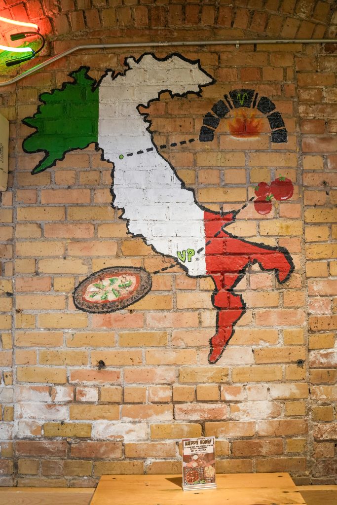 How vitta pizza became a duluth favorite 7 A hand-painted mural of italy in green, white, and red on an exposed brick wall inside vitta pizza in duluth.