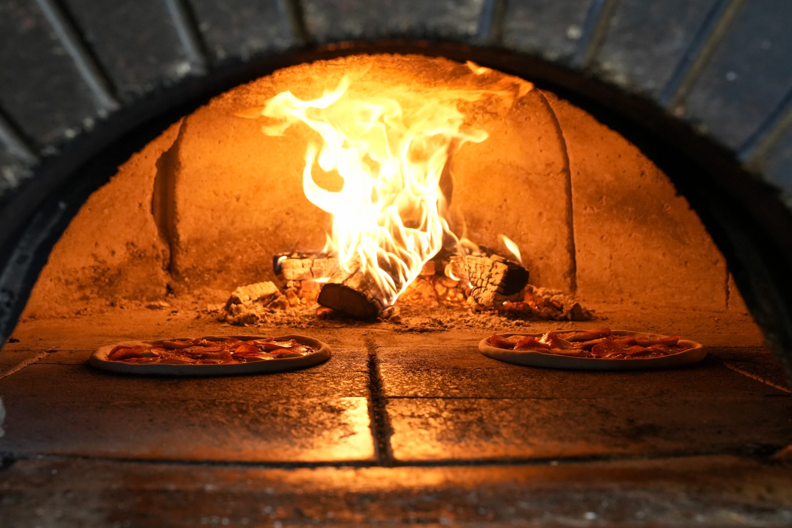 How vitta pizza became a duluth favorite 2 Pizzas cooking inside a flaming wood-fired oven at vitta pizza in duluth, minnesota.