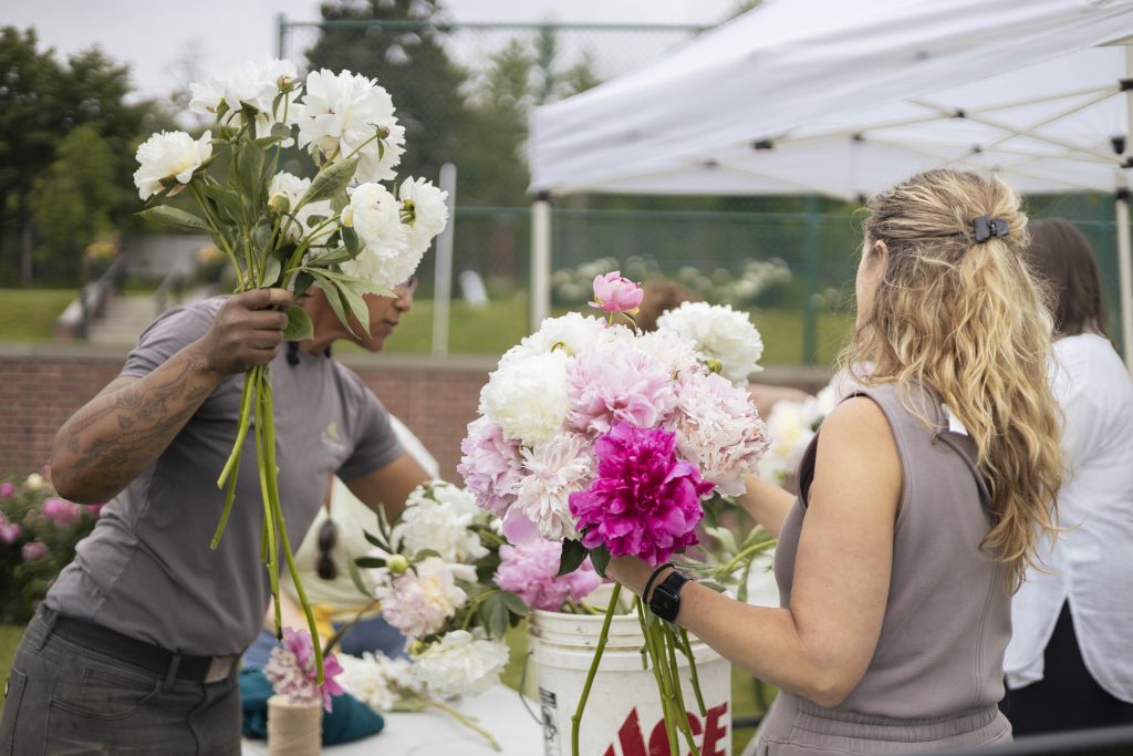 Insights from glensheen’s gardens with head gardener emily ford 11 Glensheen head gardener emily ford holds white peonies as a workshop guest builds a pink and white bouquet at glensheen's gardens.