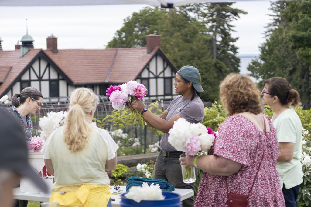 Insights from glensheen’s gardens with head gardener emily ford 13 Glensheen head gardener emily ford holds up a peony bouquet as workshop guests arrange flowers in glensheen’s gardens.